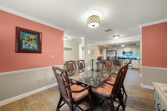 dining space with crown molding and light hardwood / wood-style flooring