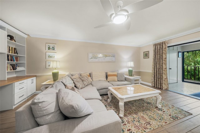 living room with built in desk, light hardwood / wood-style floors, ceiling fan, and crown molding