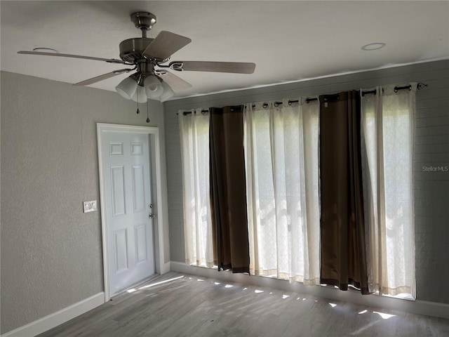 spare room featuring a wealth of natural light, ceiling fan, and hardwood / wood-style floors