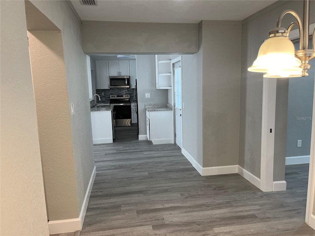 corridor featuring sink, hardwood / wood-style flooring, and a notable chandelier