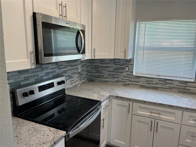 kitchen with light stone countertops, stainless steel appliances, white cabinets, and decorative backsplash