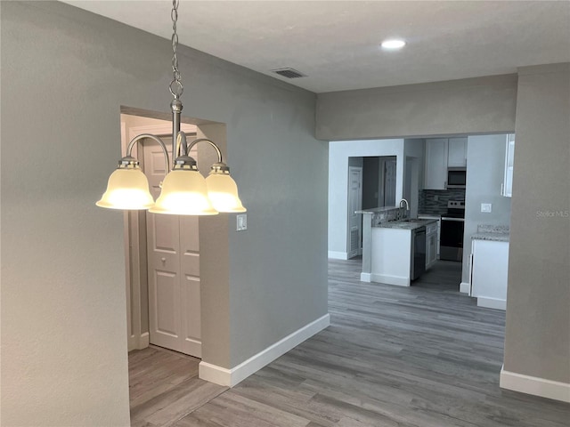 hallway with an inviting chandelier, sink, and hardwood / wood-style flooring