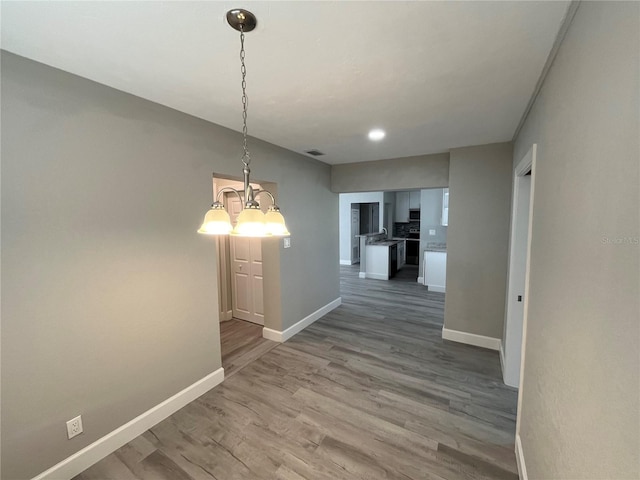 hallway featuring hardwood / wood-style floors and a chandelier