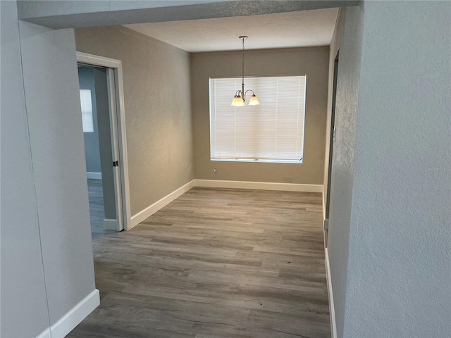 interior space with a healthy amount of sunlight, hardwood / wood-style flooring, an inviting chandelier, and a textured ceiling