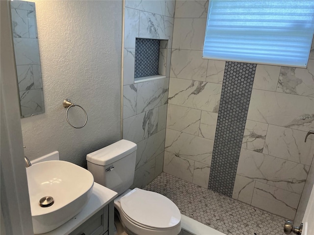 bathroom with vanity, toilet, and a tile shower