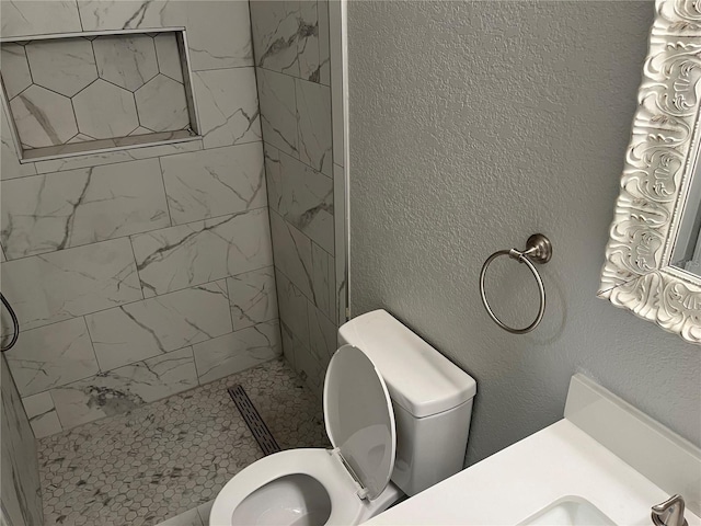 bathroom featuring vanity, toilet, and tiled shower