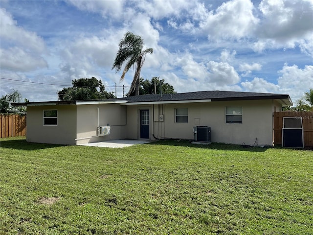 rear view of house with central AC unit, a yard, and a patio area