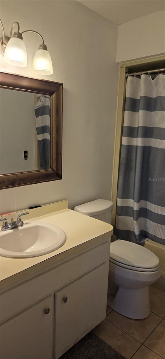 full bathroom featuring shower / bathtub combination with curtain, tile patterned flooring, toilet, and vanity