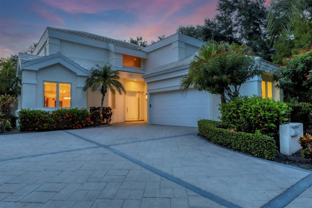 view of front facade with an attached garage, decorative driveway, and stucco siding