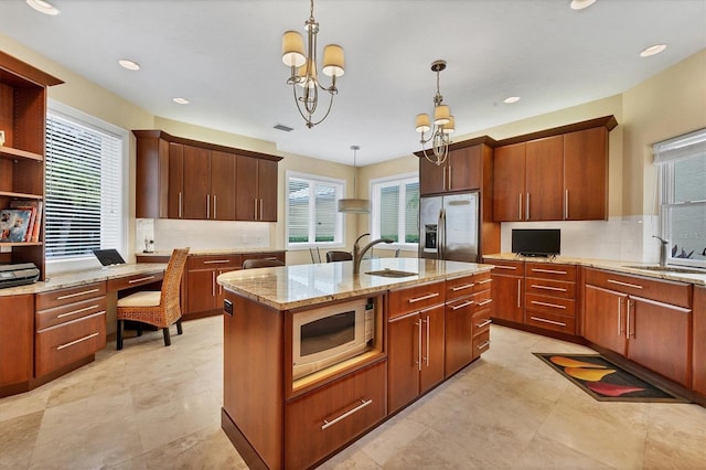 kitchen with a kitchen island with sink, decorative light fixtures, a sink, and stainless steel refrigerator with ice dispenser