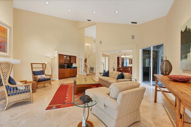 living area with a high ceiling, stairs, visible vents, and a notable chandelier