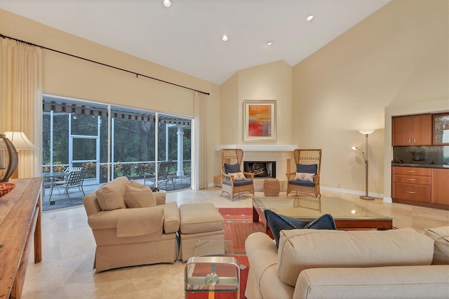 living area featuring high vaulted ceiling, a glass covered fireplace, baseboards, and recessed lighting