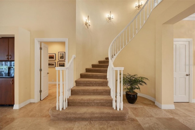 staircase with a towering ceiling and baseboards