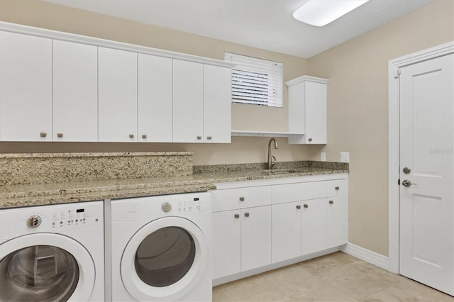 washroom featuring cabinet space, a sink, baseboards, and separate washer and dryer