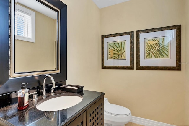 half bath featuring toilet, vanity, and baseboards