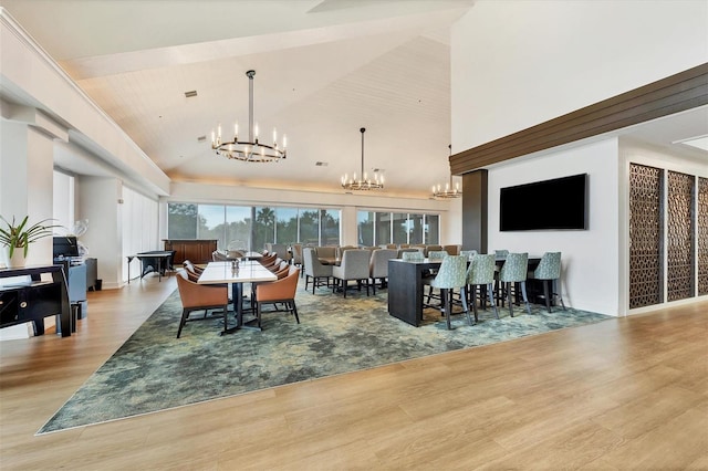 dining space featuring a chandelier, high vaulted ceiling, and light wood-style flooring