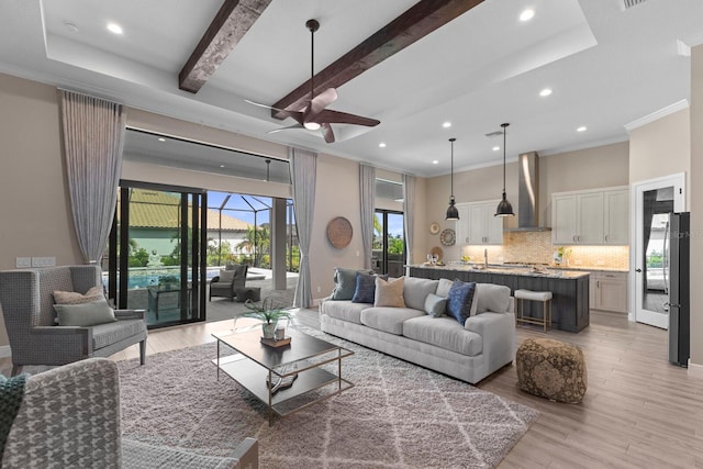 living room with ornamental molding, light wood-type flooring, ceiling fan, and beam ceiling