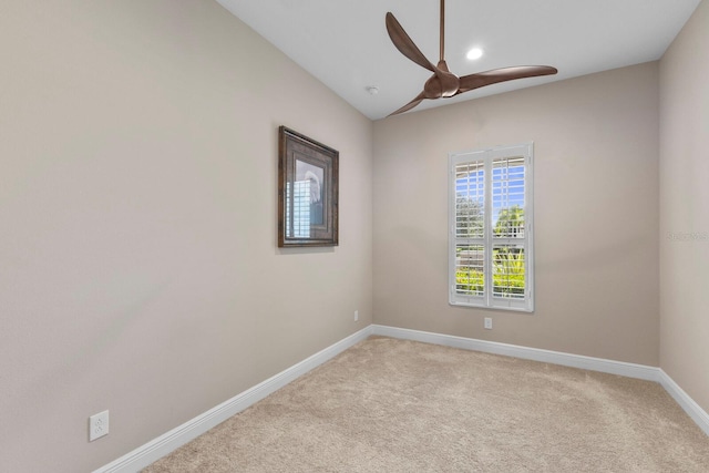 empty room featuring lofted ceiling, light carpet, and ceiling fan