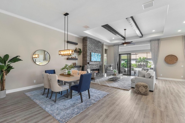 dining room featuring a fireplace, hardwood / wood-style flooring, ceiling fan, and crown molding