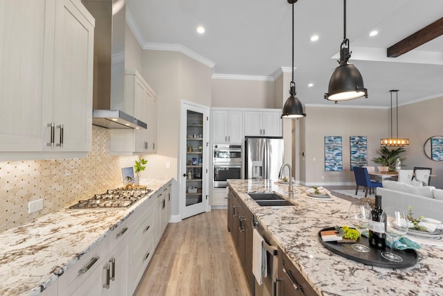 kitchen with white cabinets, stainless steel appliances, sink, and wall chimney range hood