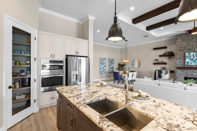 kitchen featuring white cabinetry, appliances with stainless steel finishes, beam ceiling, sink, and light hardwood / wood-style flooring