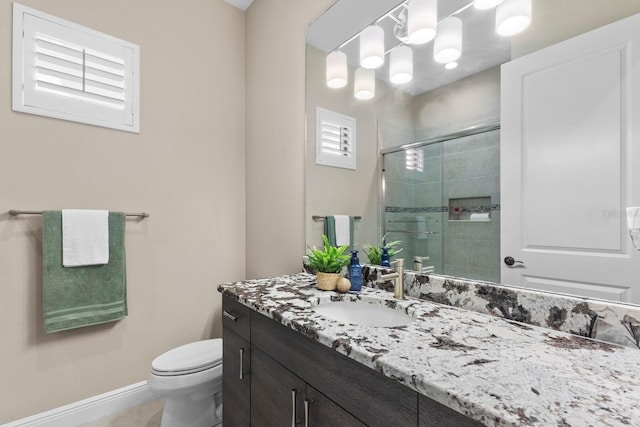 bathroom with a shower with shower door, vanity, and toilet