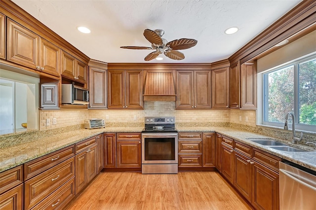 1833 Sandalwood Dr, Sarasota, FL 34231 - kitchen featuring stainless steel appliances, a sink, custom exhaust hood, ceiling fan, and light wood-style flooring