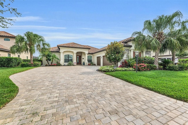 mediterranean / spanish home with a garage and a front lawn