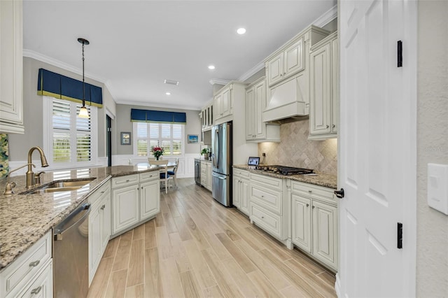 kitchen with light hardwood / wood-style flooring, sink, light stone countertops, hanging light fixtures, and appliances with stainless steel finishes