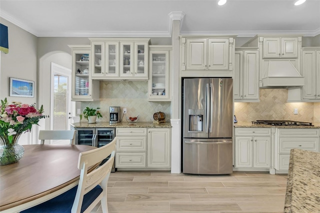 kitchen with light hardwood / wood-style flooring, stainless steel appliances, premium range hood, light stone countertops, and white cabinets