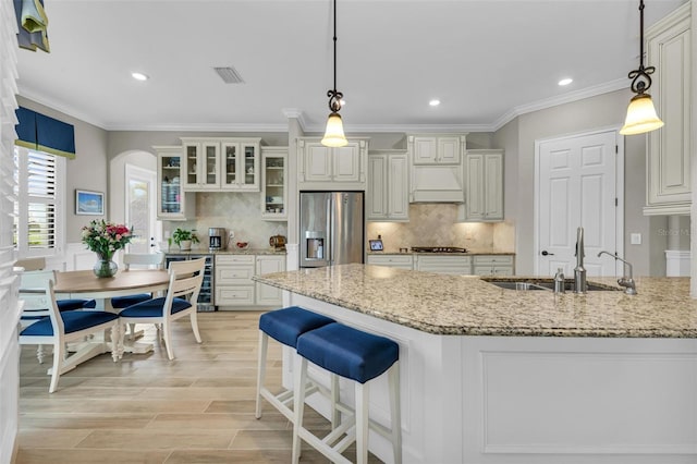 kitchen featuring decorative light fixtures, light wood-type flooring, stainless steel fridge with ice dispenser, and sink