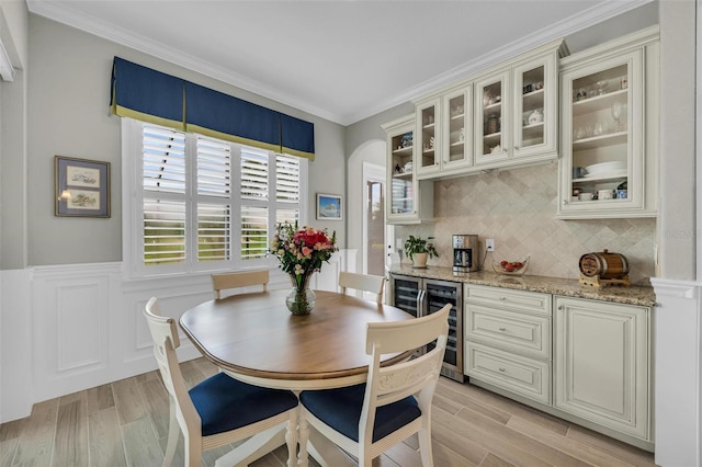 dining room with ornamental molding, wine cooler, and light hardwood / wood-style floors