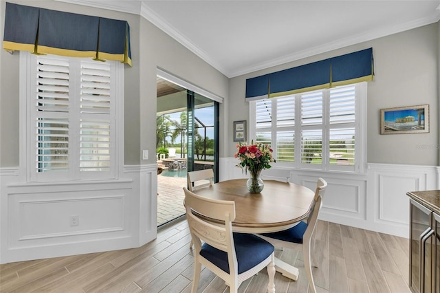 dining area with ornamental molding and light hardwood / wood-style flooring