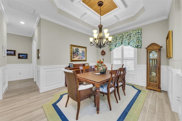 dining area featuring crown molding, an inviting chandelier, light wood-type flooring, and a tray ceiling