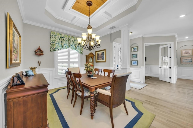 dining space with crown molding, light wood-type flooring, and an inviting chandelier