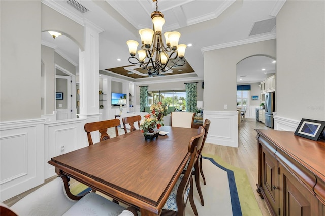 dining space featuring crown molding, light wood-type flooring, and a notable chandelier