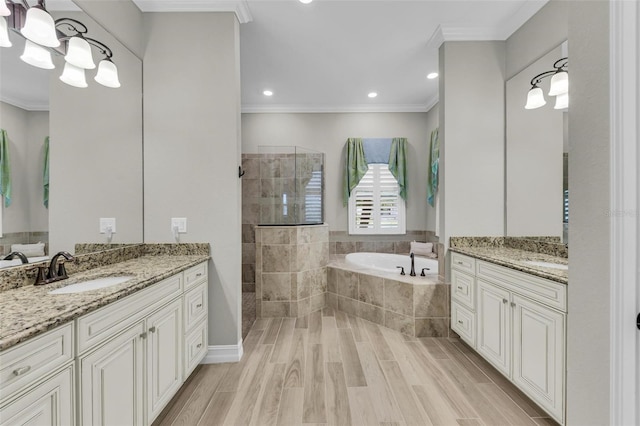 bathroom featuring plus walk in shower, hardwood / wood-style floors, ornamental molding, and vanity