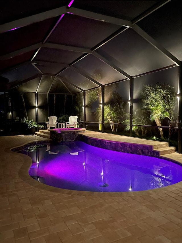 view of swimming pool featuring glass enclosure and a patio area