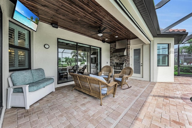 view of patio with grilling area, glass enclosure, an outdoor kitchen, and ceiling fan