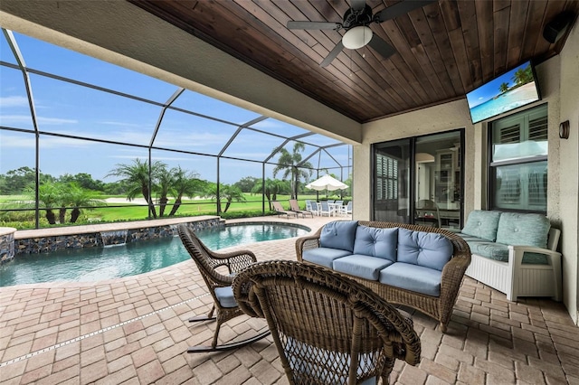 view of patio / terrace with a lanai, an outdoor hangout area, ceiling fan, and pool water feature