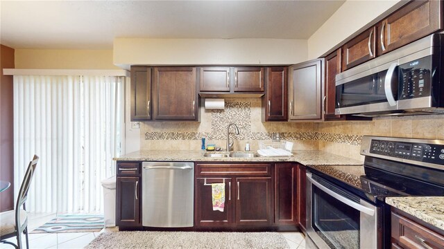 kitchen featuring tasteful backsplash, sink, stainless steel appliances, light tile patterned floors, and light stone countertops