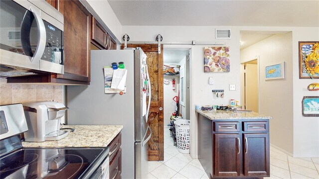 kitchen with light stone countertops, stove, light tile patterned flooring, and a barn door