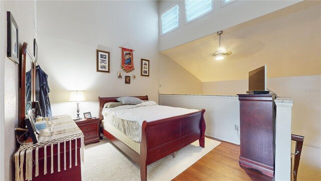 bedroom featuring light wood-type flooring, ceiling fan, and high vaulted ceiling