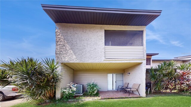 rear view of property with cooling unit, a lawn, and a patio