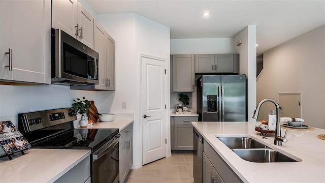 kitchen featuring gray cabinets, appliances with stainless steel finishes, light tile patterned floors, and sink