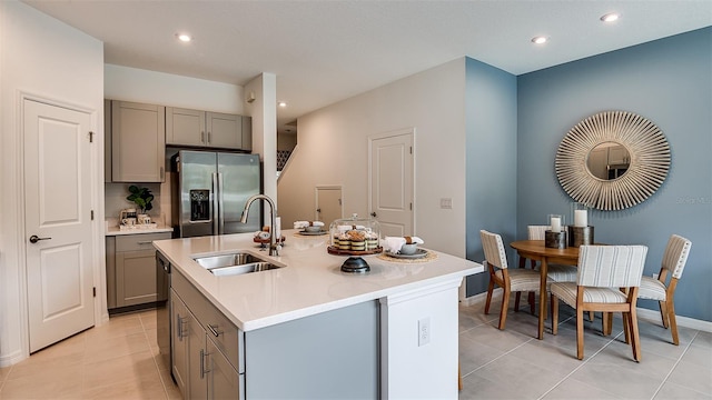 kitchen with gray cabinets, appliances with stainless steel finishes, an island with sink, and sink