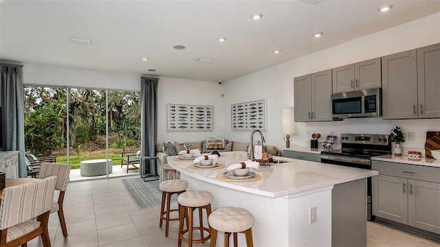 kitchen featuring gray cabinetry, stainless steel appliances, an island with sink, and sink