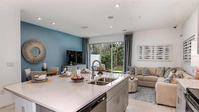 kitchen featuring appliances with stainless steel finishes, light tile patterned floors, an island with sink, and sink