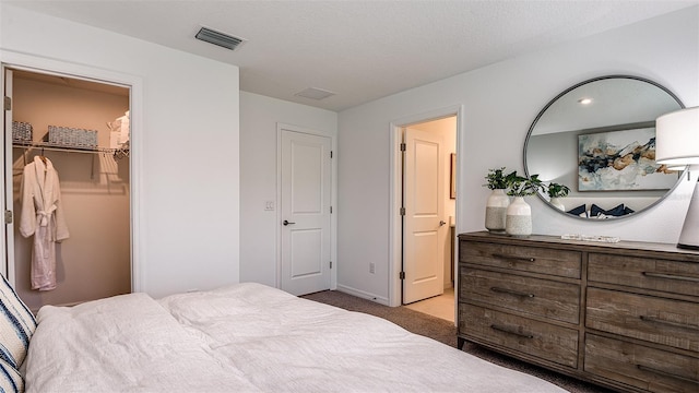 carpeted bedroom with a textured ceiling, a walk in closet, and a closet