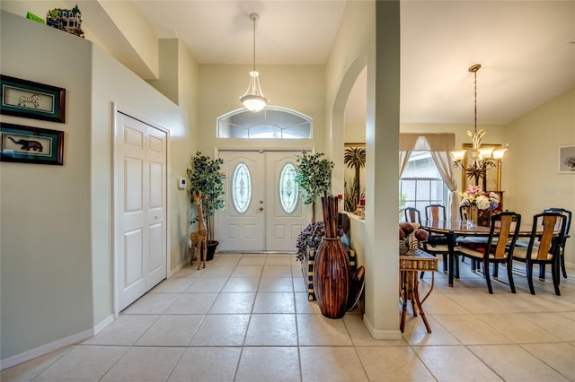 foyer entrance with light tile patterned flooring, plenty of natural light, and a chandelier